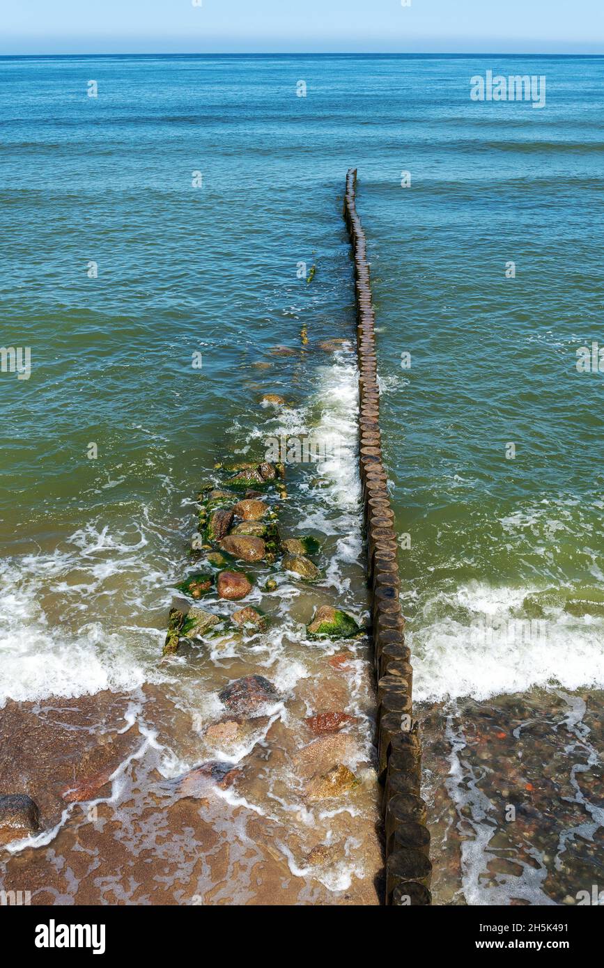 A breakwater made of logs cuts through the sea wave. The Baltic Sea ...