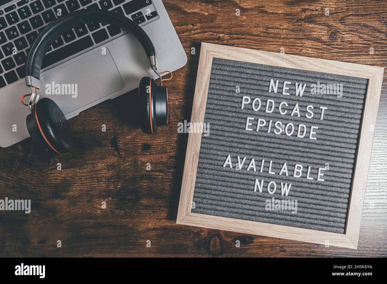top view of letter board with text NEW PODCAST EPISODE on wooden table with laptop and headphones, podcasting concept Stock Photo