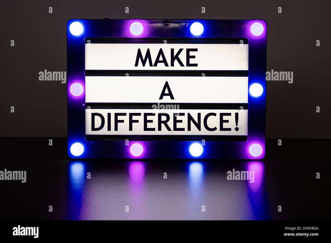 Lightbox with green lights in dark room with words make a difference