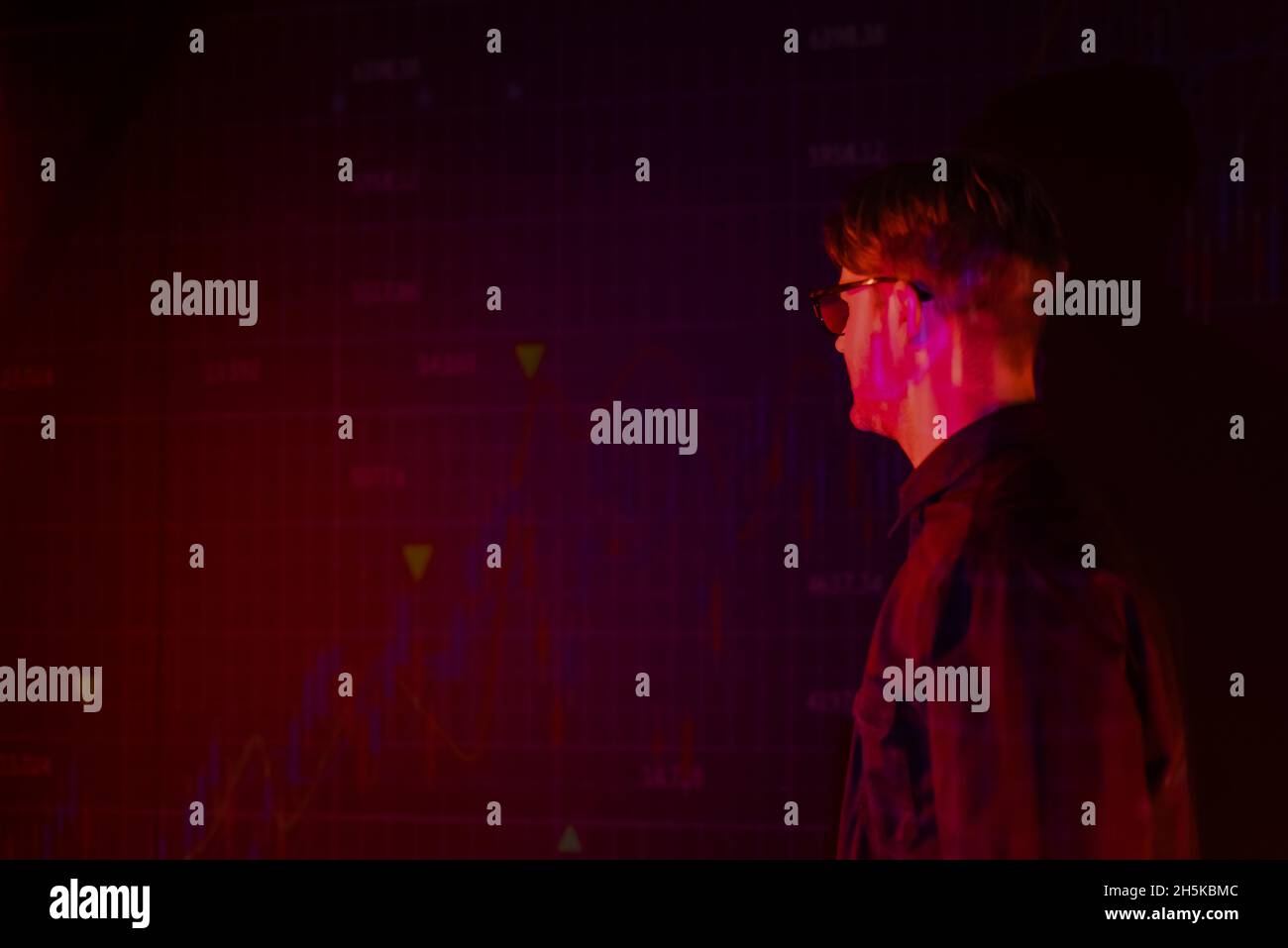 Young programmer looking at charts reflection on black background Stock Photo
