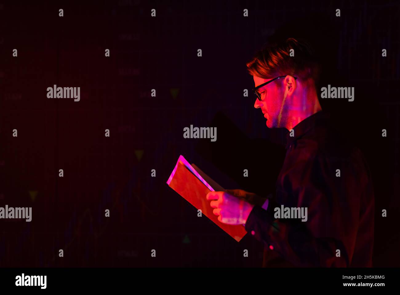Side view of programmer holding paper folder isolated on black Stock Photo