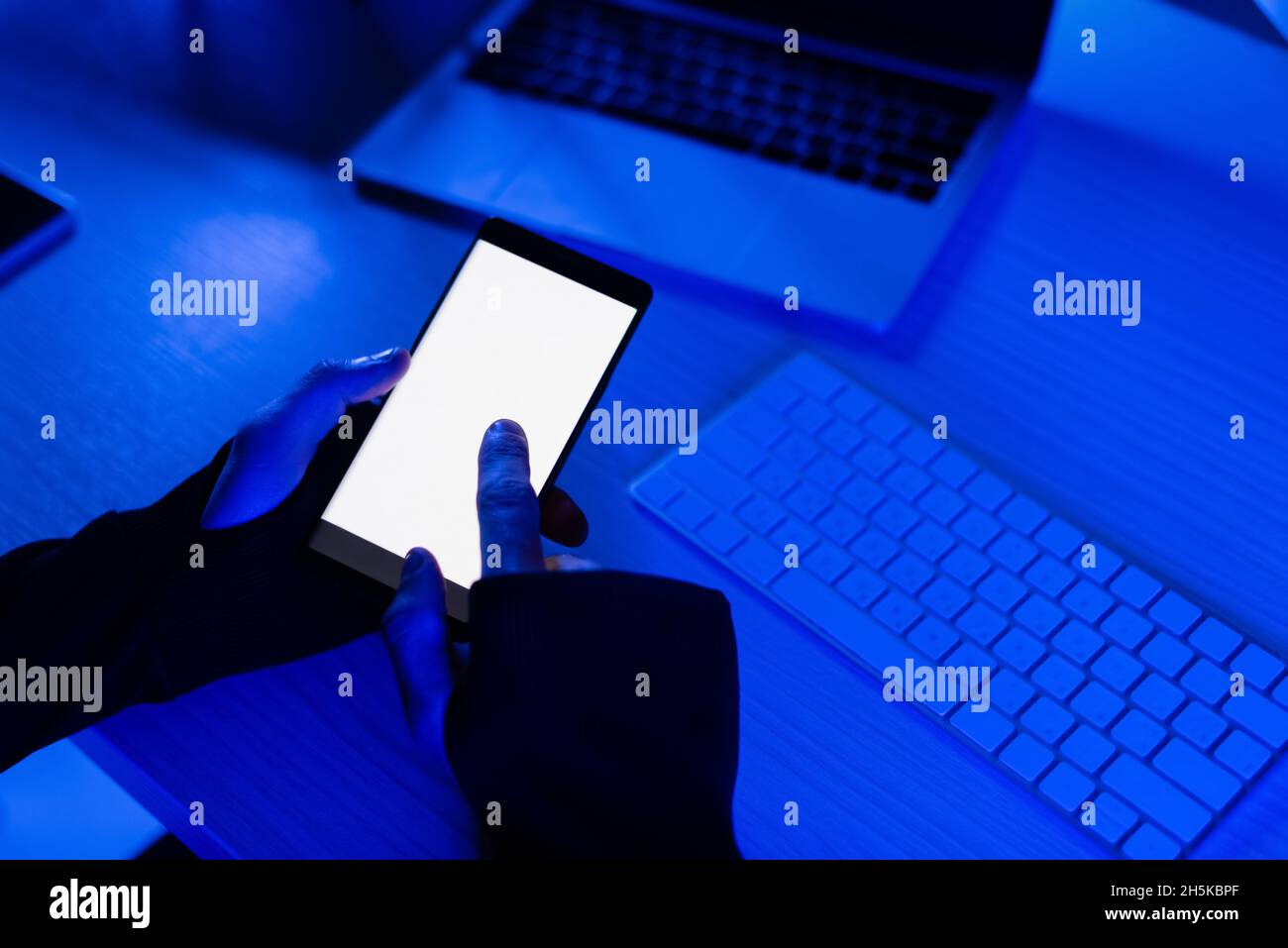 Cropped view of programmer using smartphone near laptop and computer keyboard on table Stock Photo
