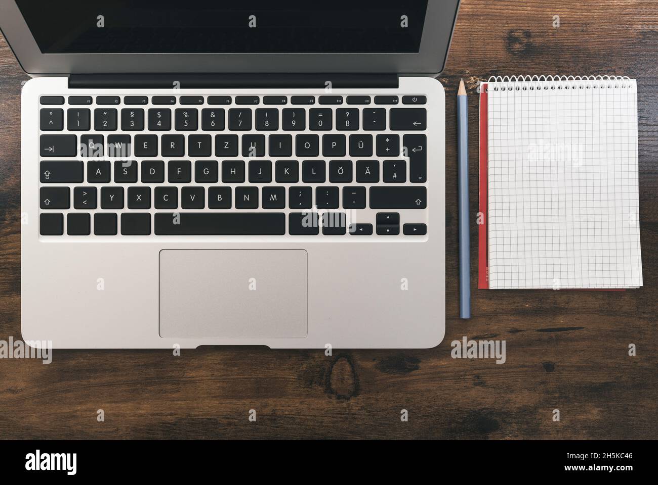 top view of laptop computer and blank note pad with pencil on wooden desk Stock Photo