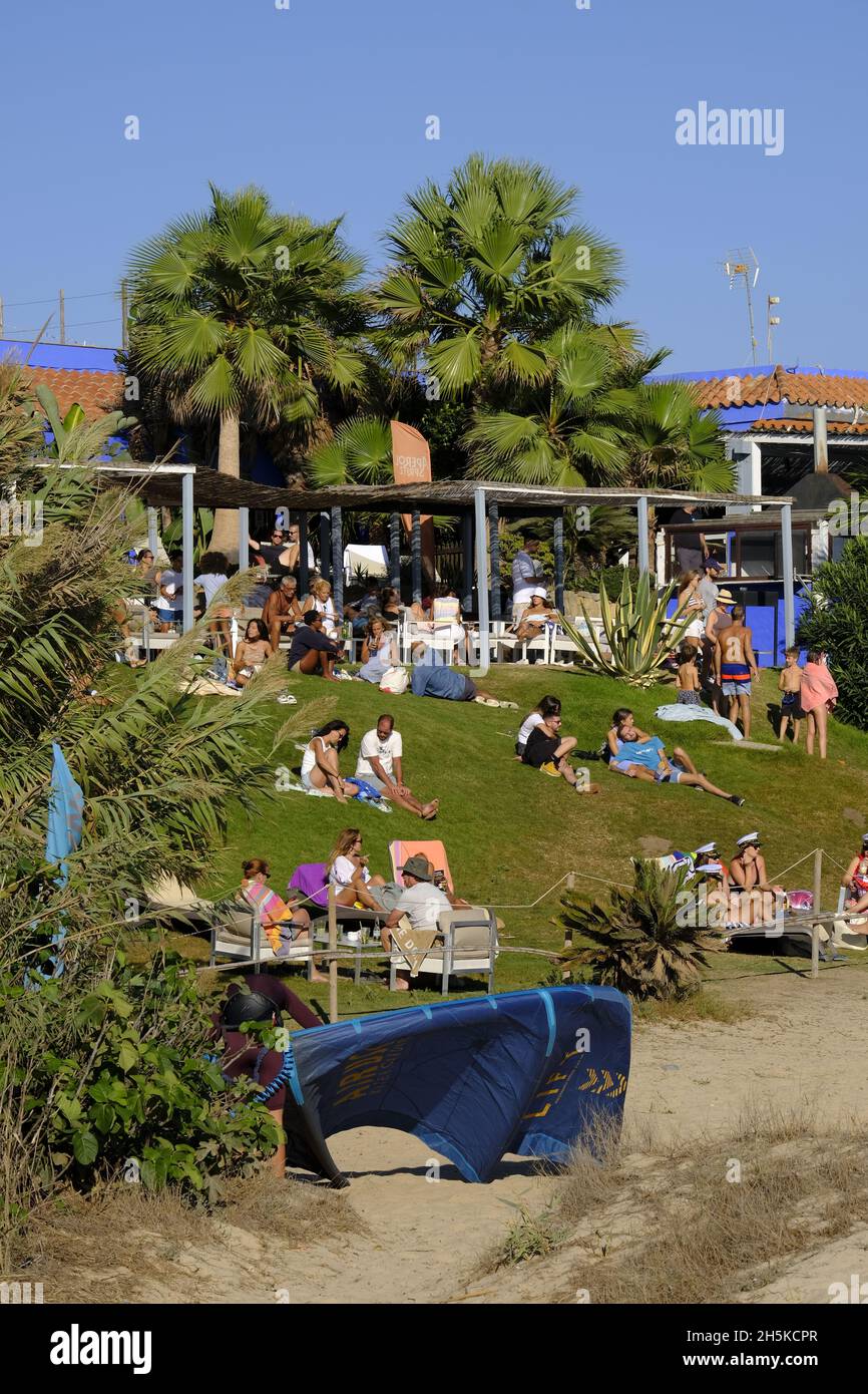 Tourists and local relaxing on the grass in front of a chiringuito on Los Lances beach. Tarifa, Costa de la Luz, Cadiz Province, Andalucia, spain Stock Photo