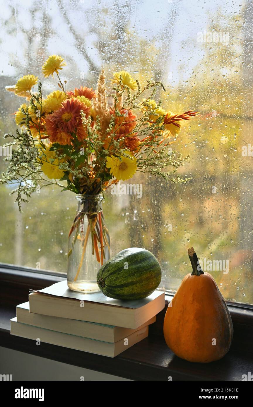 Autumn Bouquet Of Flowers, Pumpkins And Books in A Rainy Day Stock Photo