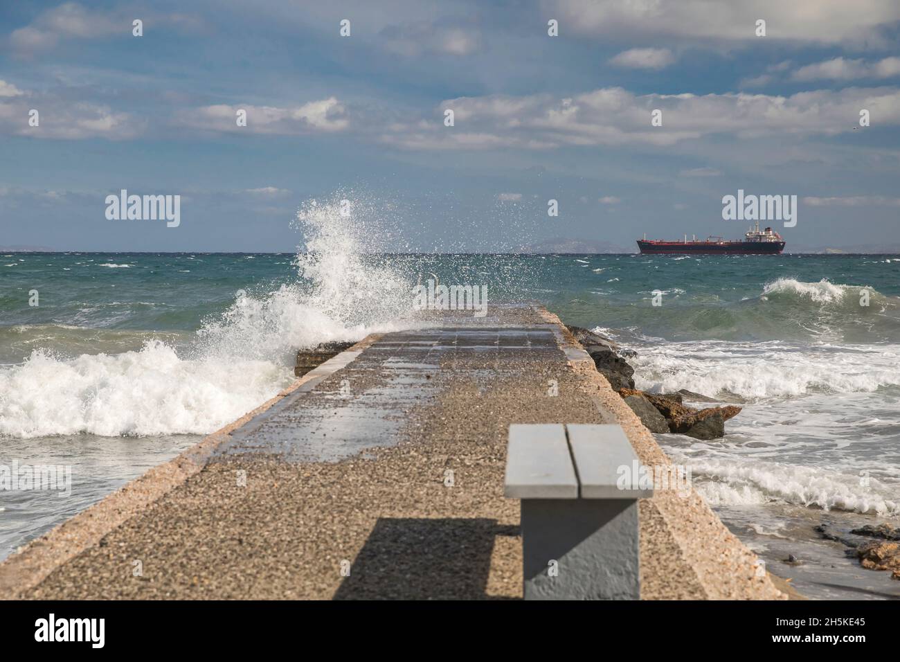 Jetty on a windy day. Cargo ship in the distance. Stock Image. Stock Photo