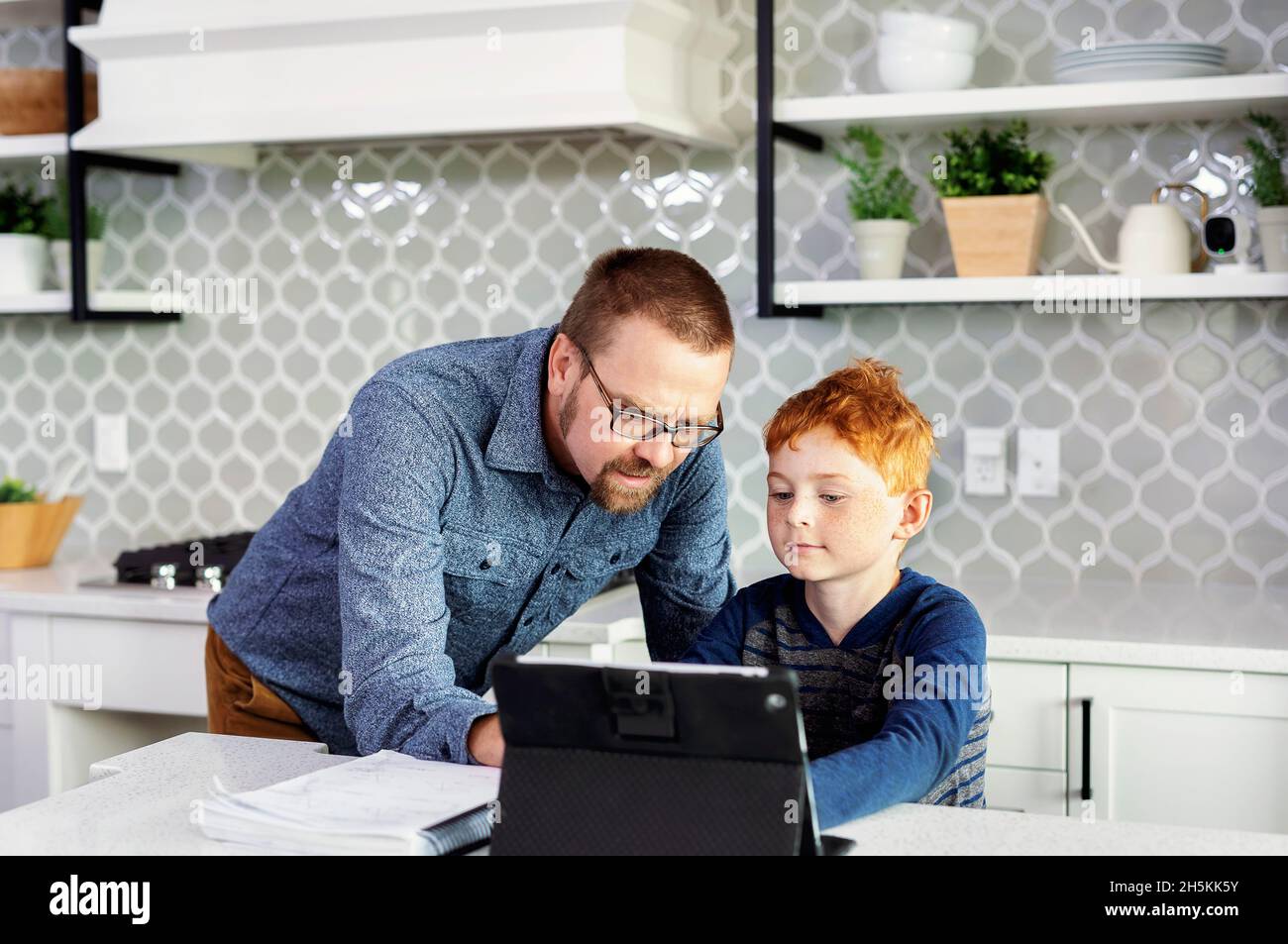 Father helping son with homework in the home kitchen; Edmonton, Alberta, Canada Stock Photo
