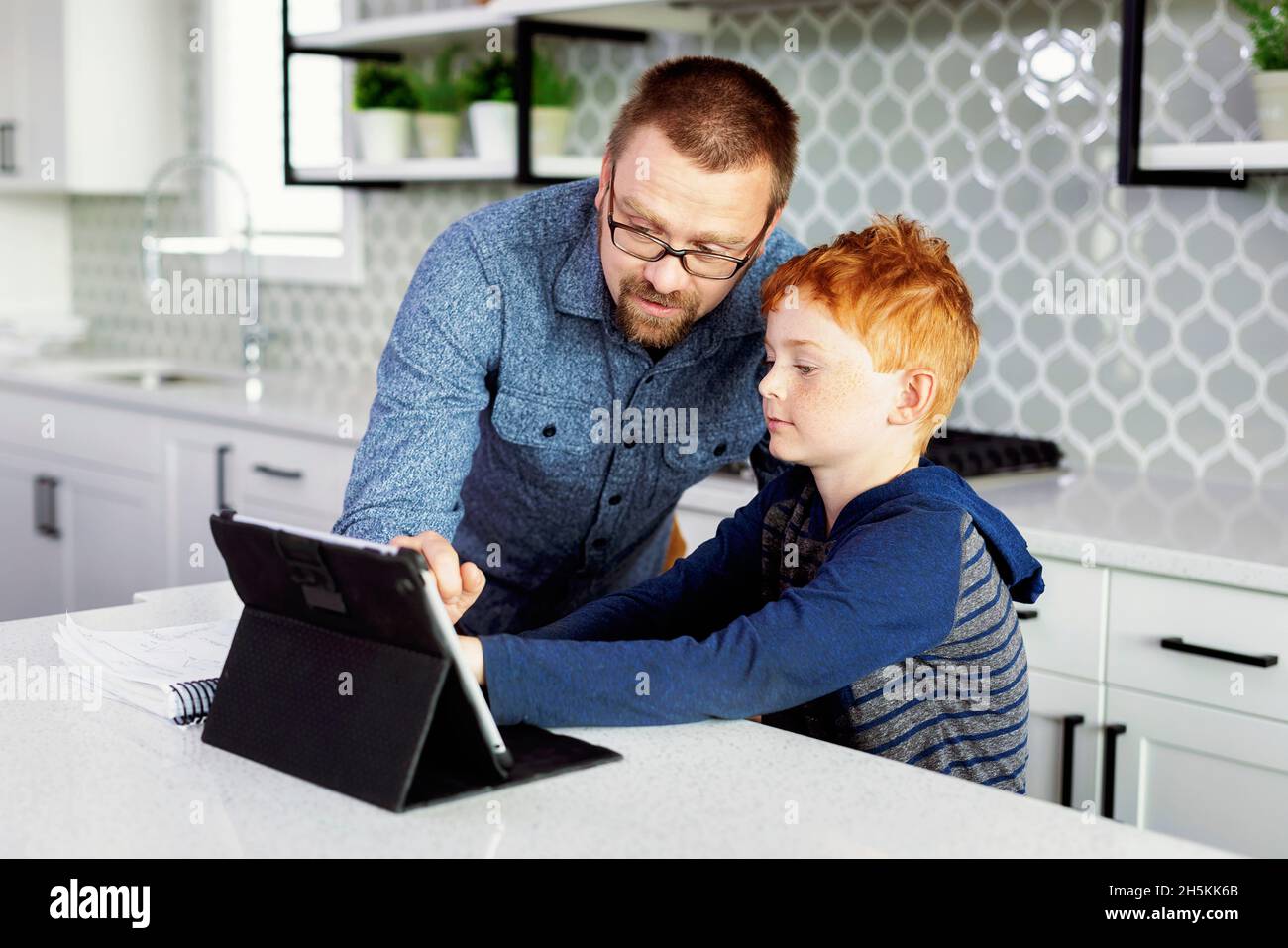 Father helping son with homework in the home kitchen; Edmonton, Alberta, Canada Stock Photo