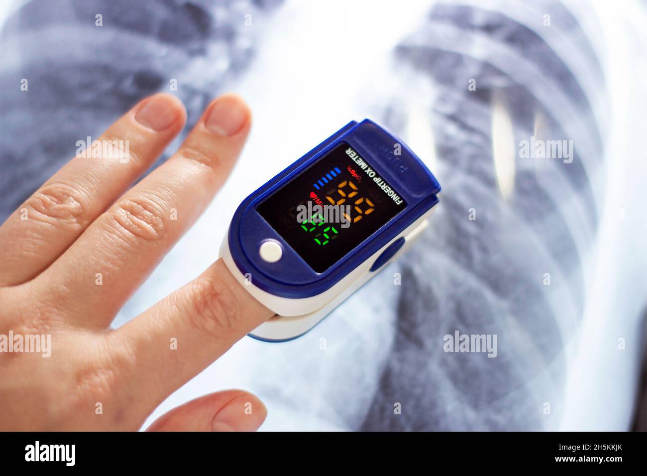 Woman hand with medical fingertip pulse oximeter tool for oxygen saturation check during covid virus desease. SpO2 monitoring and heart rate measureme Stock Photo