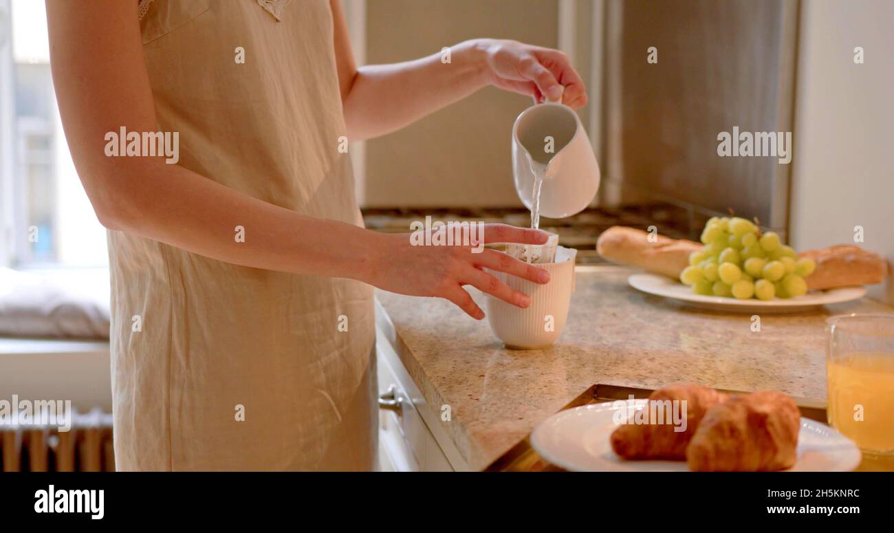A woman is preparing a beverage in a kitchen Stock Photo