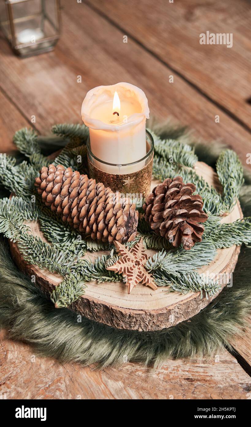 rustic style Christmas centerpiece with a lit candle and pine cones on a  wooden table, concept christmas and advent decoration Stock Photo - Alamy, image size:819x1390