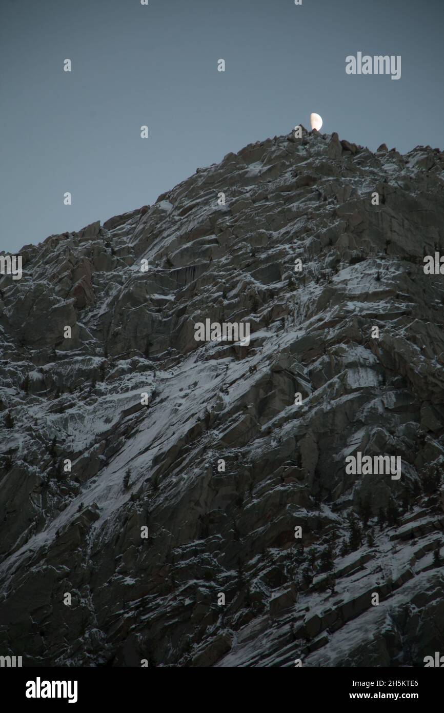 The moon rises above the first snow on Lone Pine peak. Stock Photo