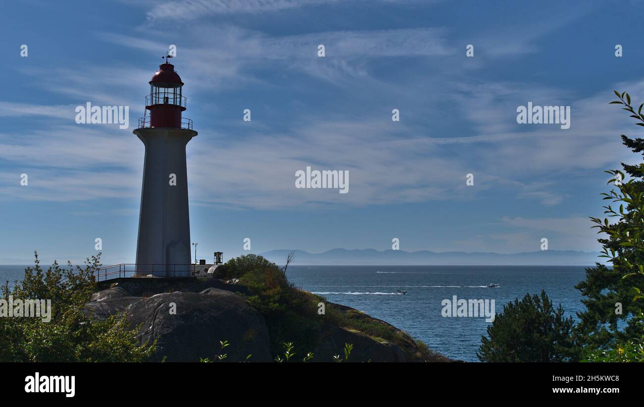 View of Point Atkinson Lighthouse on the shore of Lighthouse Park in West Vancouver, British Columbia, Canada with Pacific Ocean and mountains. Stock Photo