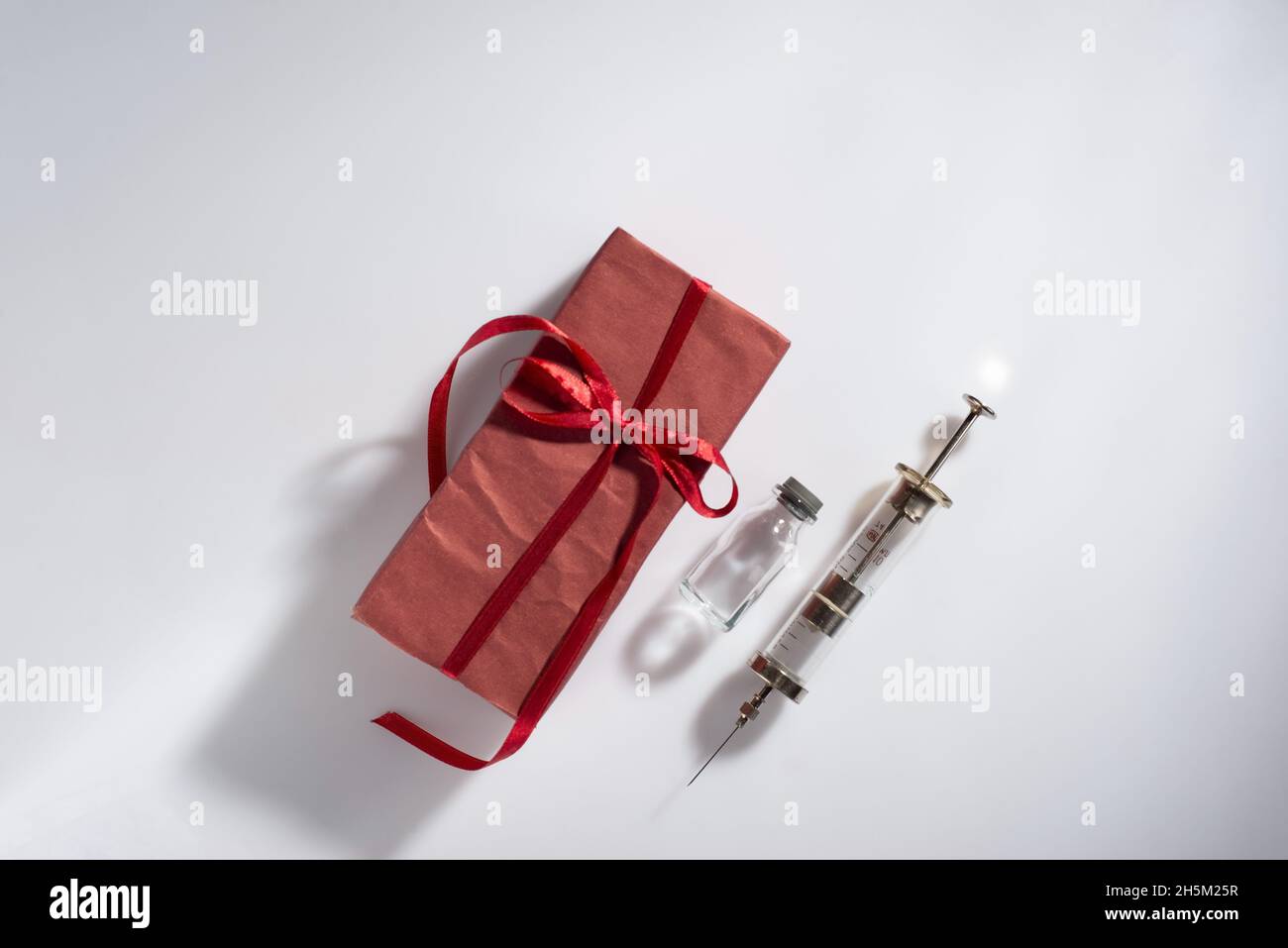 red vaccine gift with syringe on white background Creative Coronavirus or 2019-nCoV or COVID-19 vaccine Stock Photo