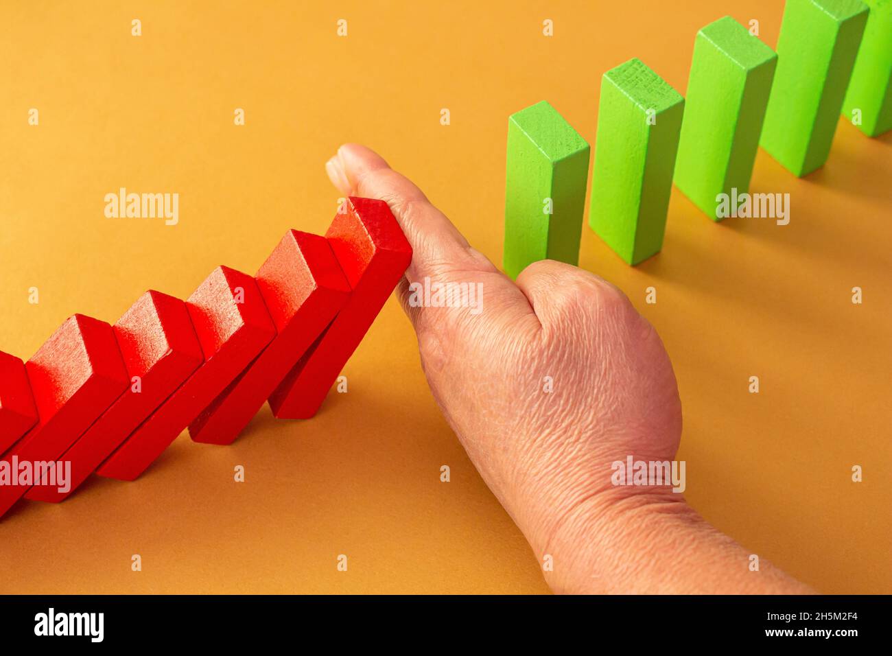 Close up business woman hand stopping wooden blocks from falling. Concept of risk and crisis management in business life. Stock Photo