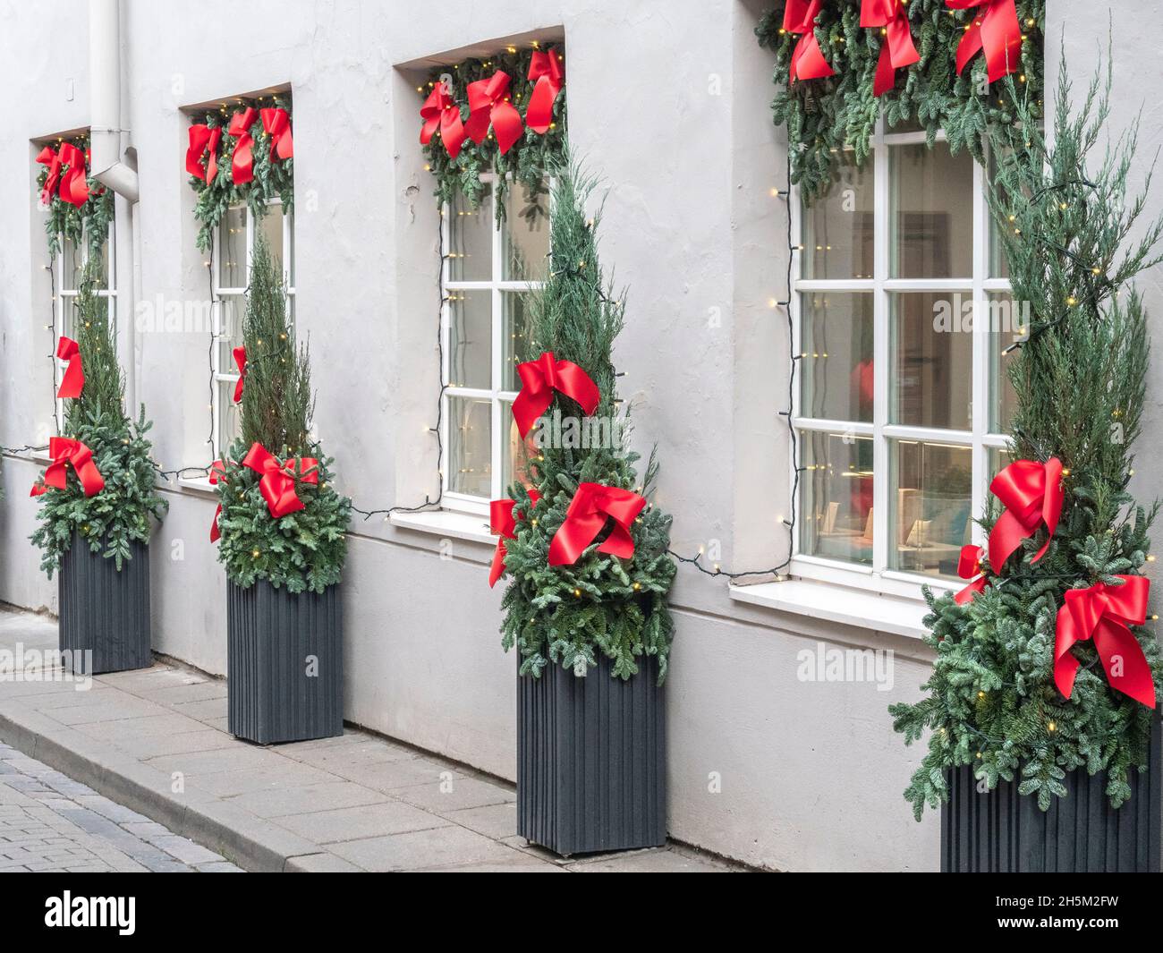 Building front decorated to Christmas with christmas trees fir branches, decorations and garland lights Stock Photo