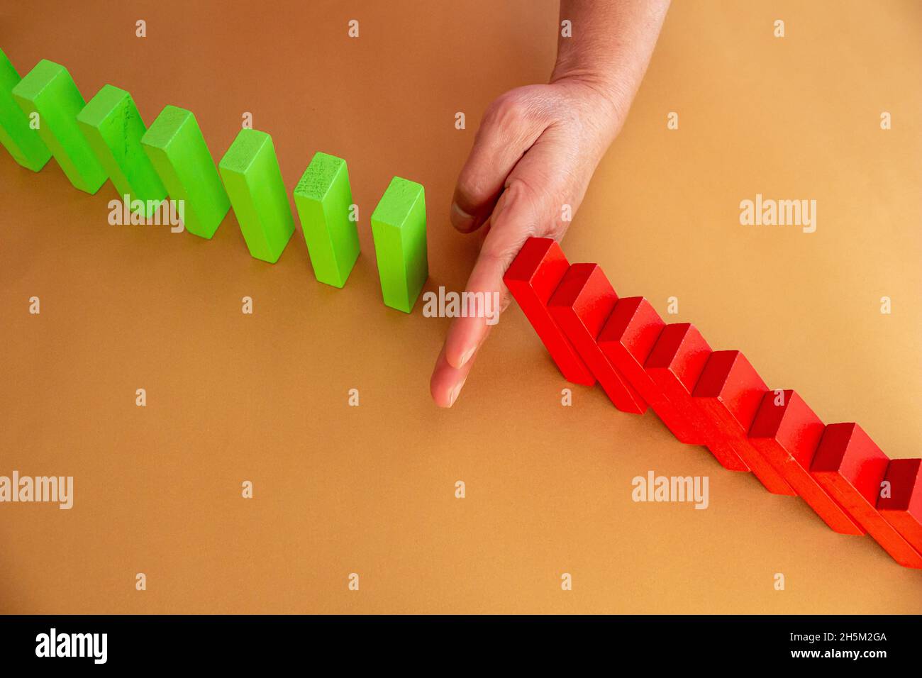 Close up business woman hand stopping wooden blocks from falling. Concept of risk and crisis management in business life. Stock Photo