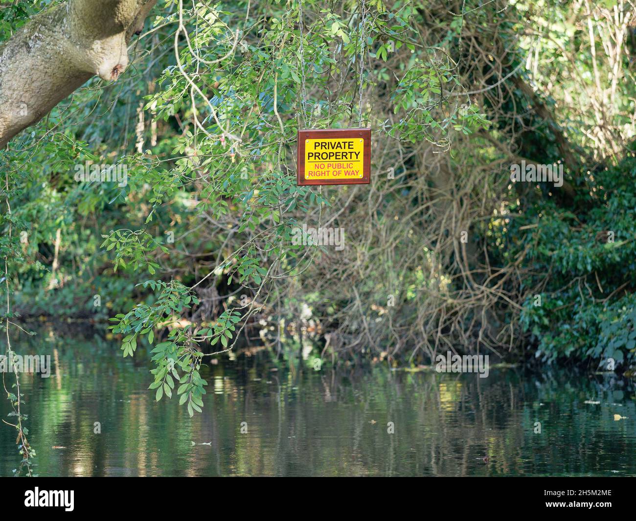 A private property sign hanging over a branch of the River Gade, Grand Union Canal in Hertfordshire Stock Photo