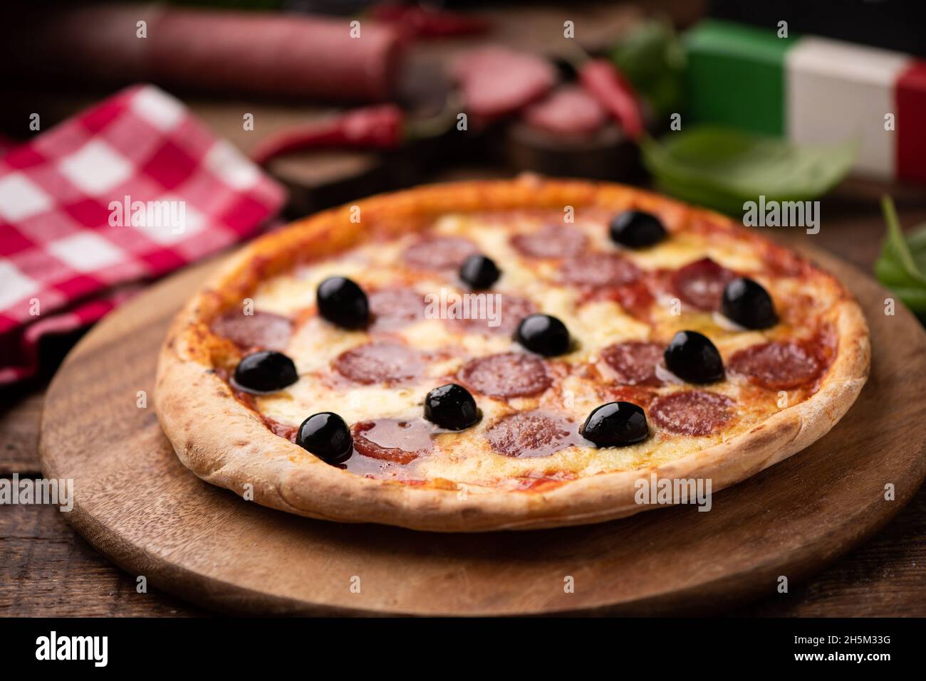 Pizza slice with olives and salami toping on wooden table close up Stock Photo