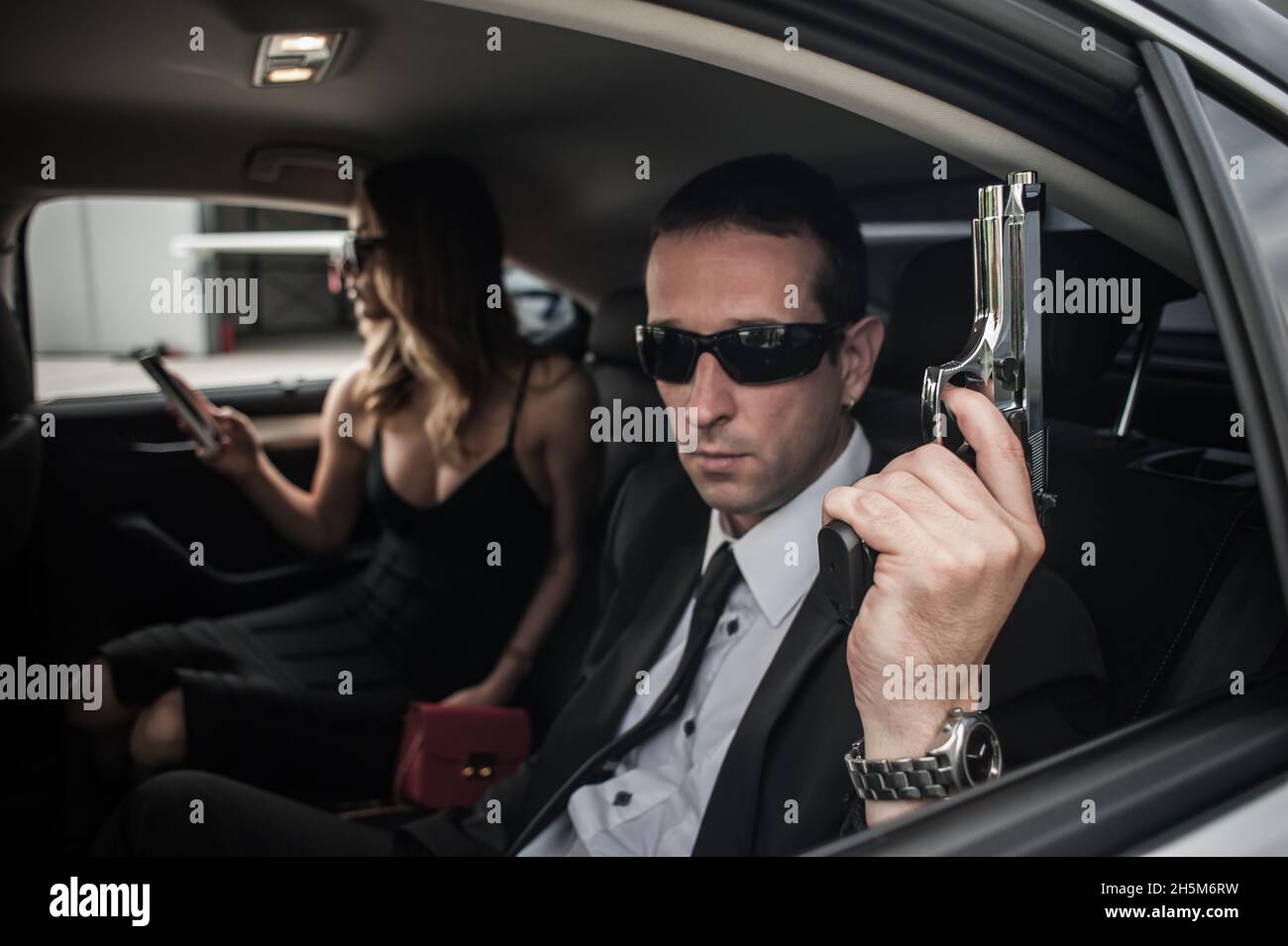 Agent in civilian black suit with gun protect celebrity person in the