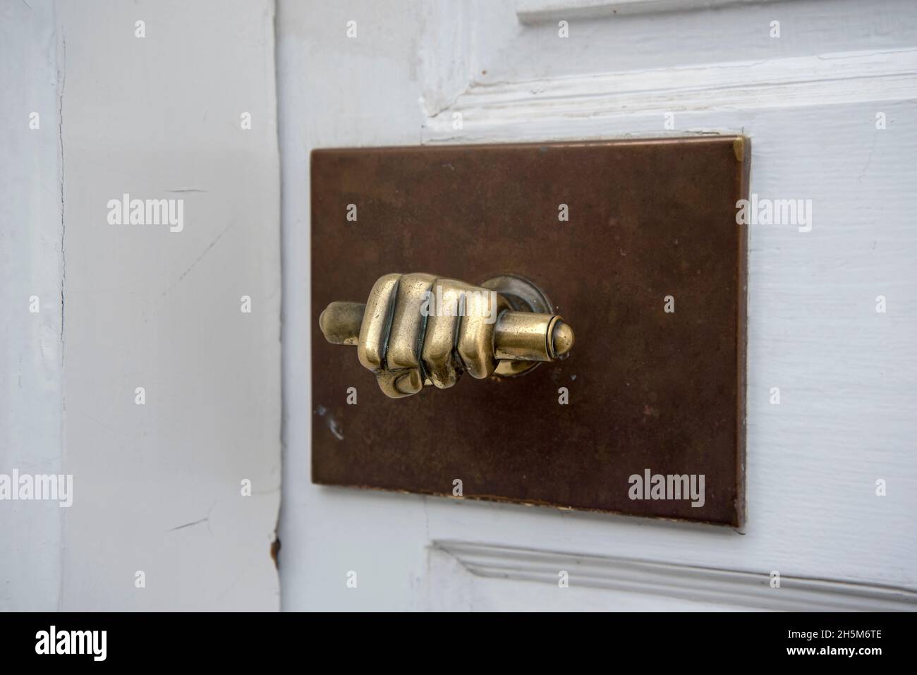 Unusual brass door handle in the shape of a hand holding a scroll in