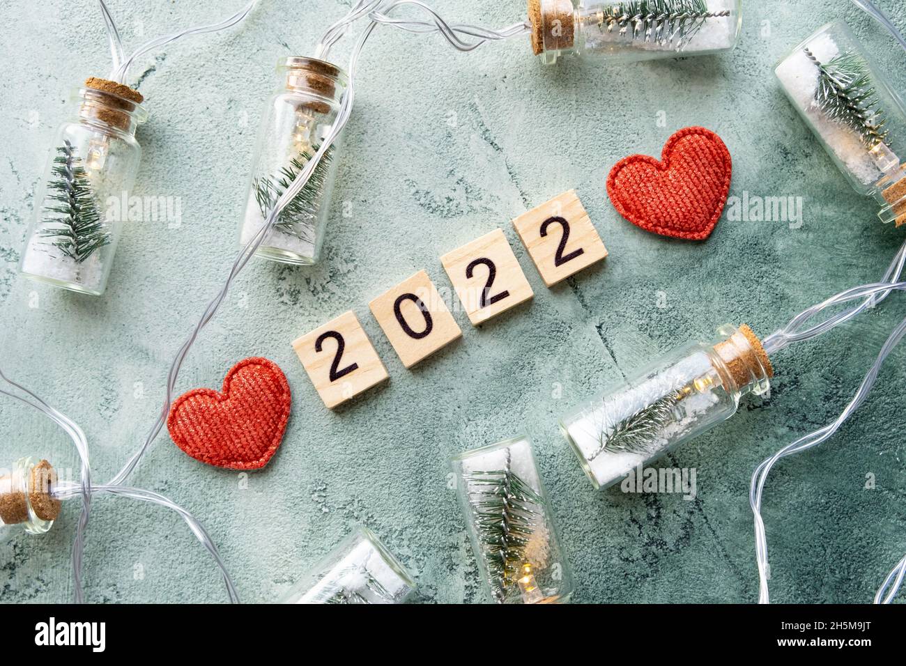 Number 2022 on wooden squares and new year decorations on a beautiful textured green background diagonally. New year and christmas concept. Top view Stock Photo