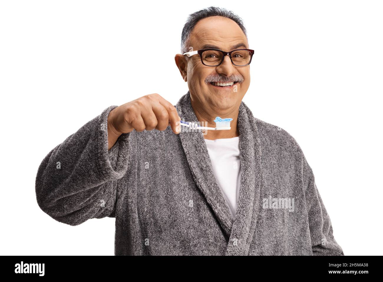 Happy mature man in a bathrobe holding a toothbrush with toothpaste isolated on white background Stock Photo