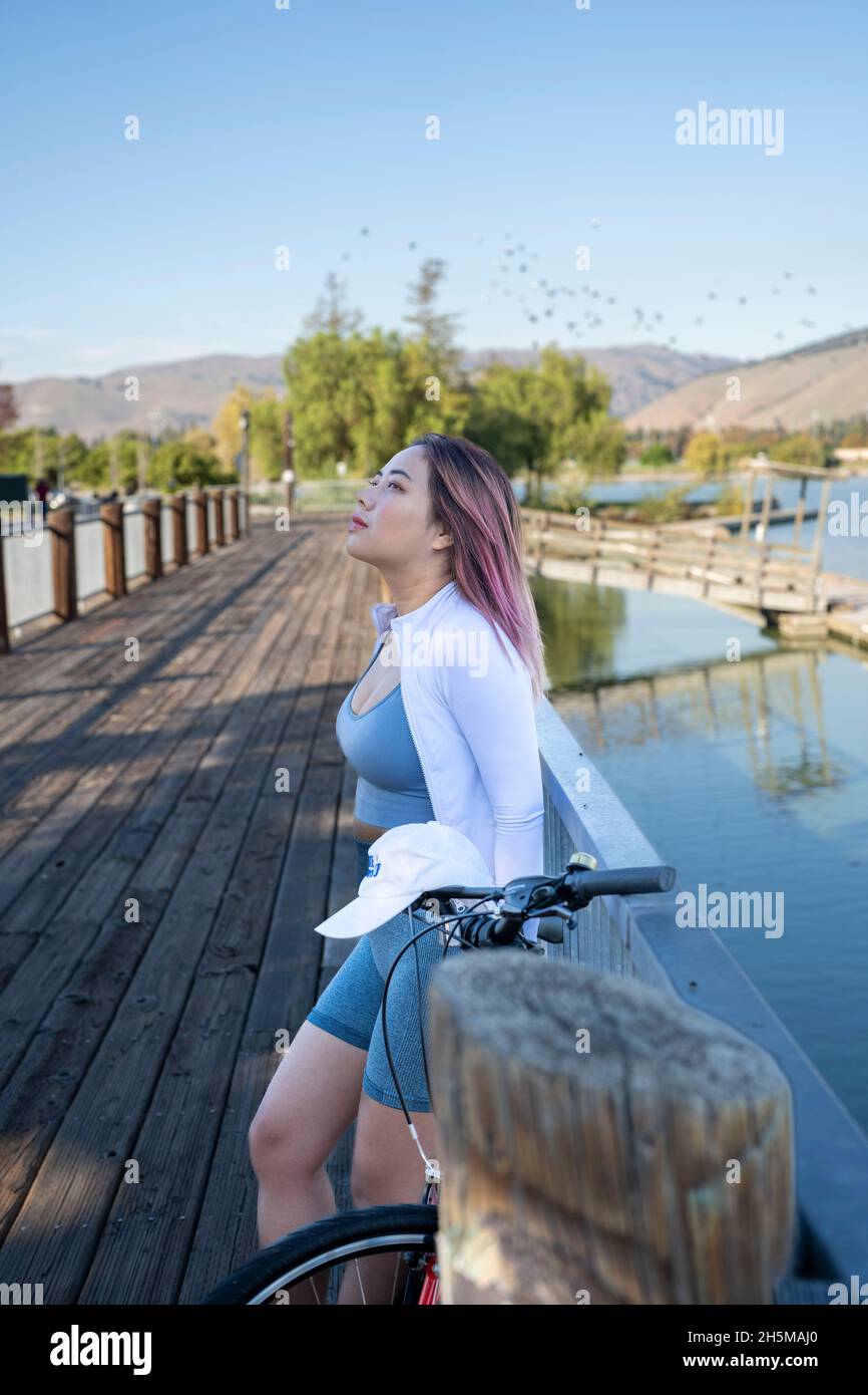 Young Asian Woman with Bicycle on Lakeside Boat Dock Stock Photo