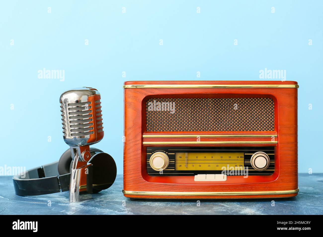 Retro radio receiver with microphone and headphones on color background
