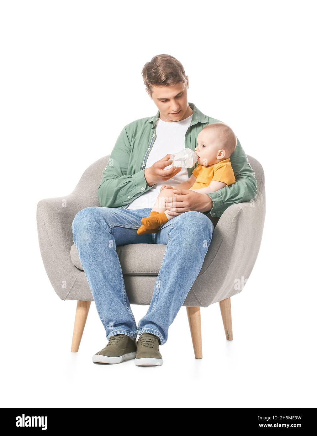 Young father feeding little baby in armchair on white background Stock