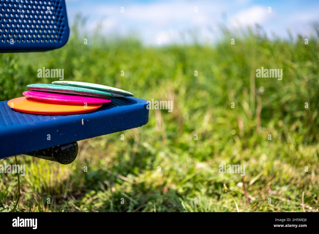 Pile of discs resting on a bench in the golf course park Stock Photo