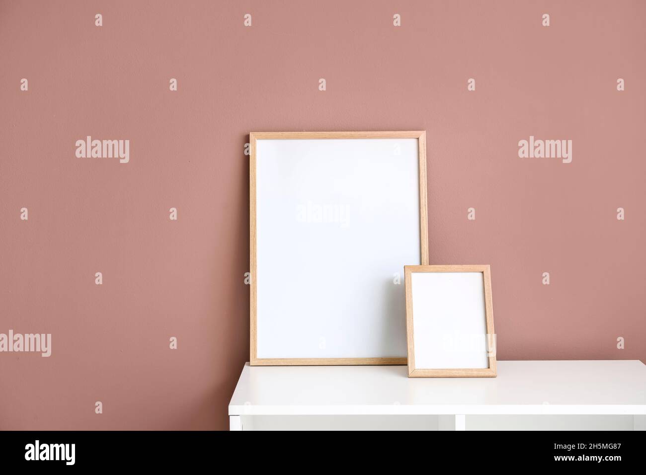 Blank frames on white shelf near color wall Stock Photo - Alamy