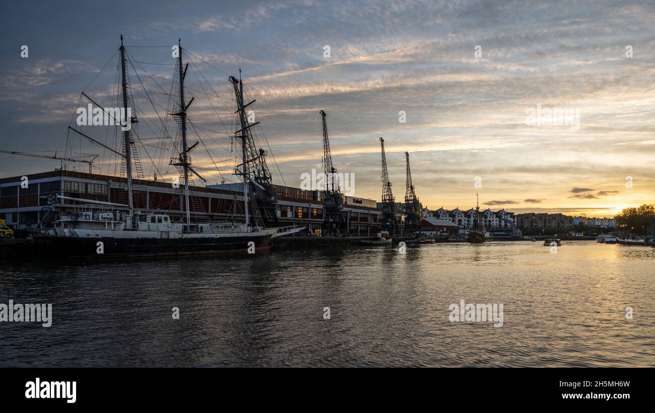 The sun sets over the M Shed museum and historic ships docked on Bristol's Harbourside. Stock Photo