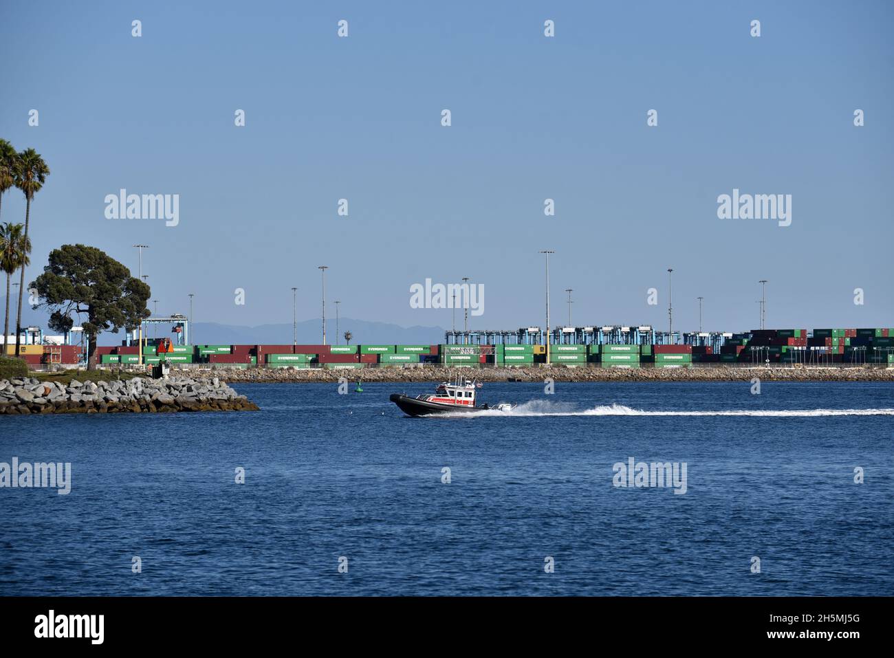 Los Angeles, CA USA - October 15, 2021: Small boat passing the shipping containers and gantry cranes in the main channel of the Port of Los Angeles on Stock Photo