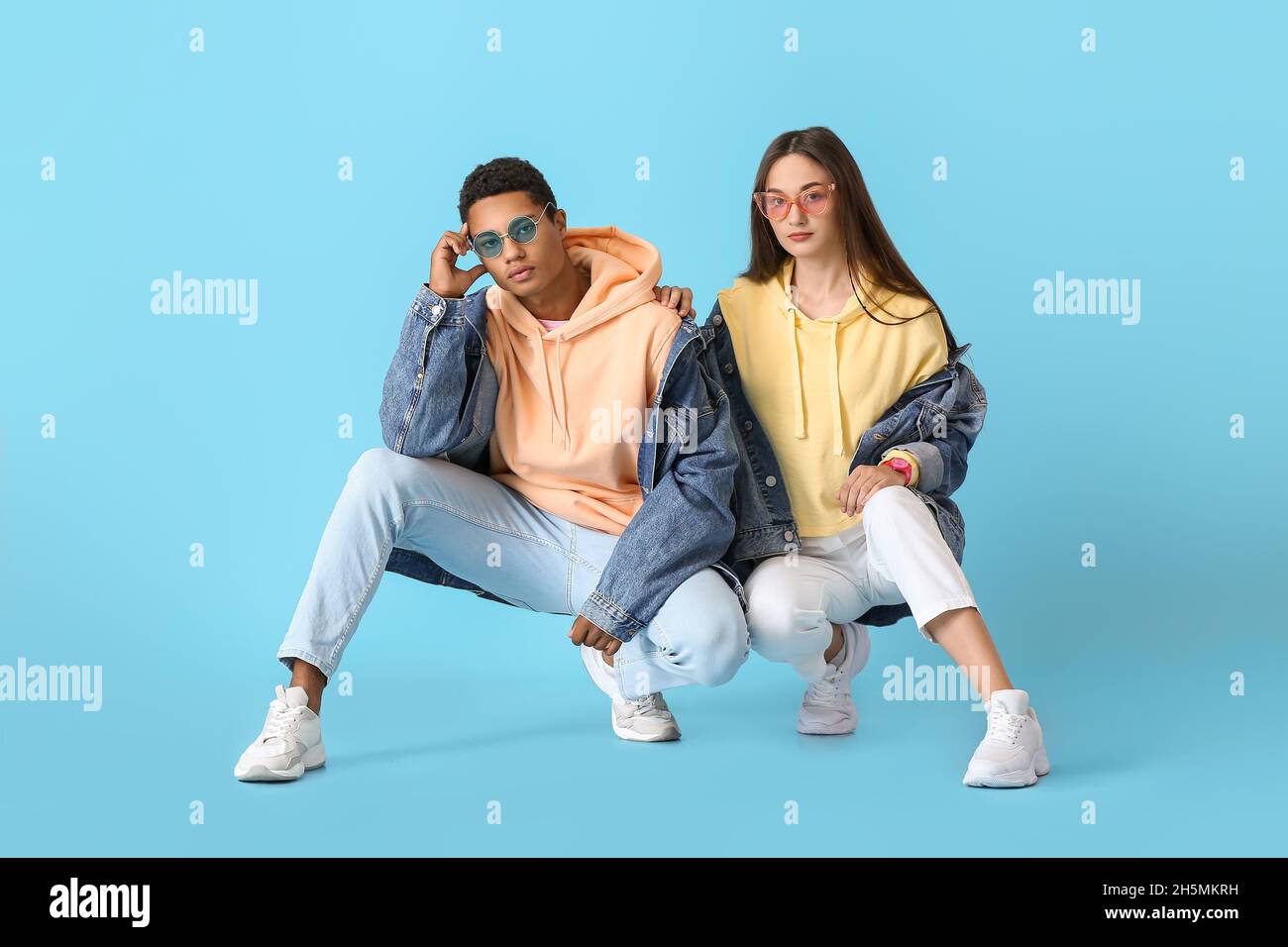 Stylish young couple in hoodies on blue background Stock Photo