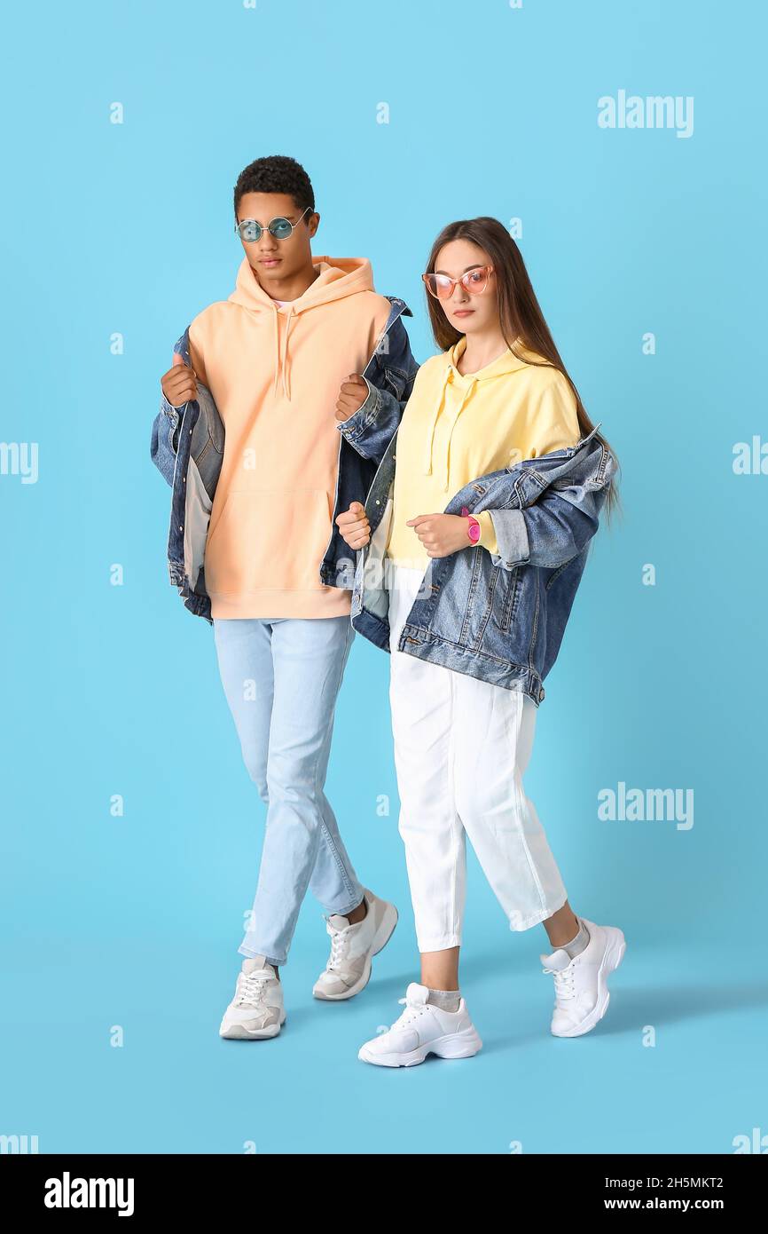 Stylish young couple in hoodies on blue background Stock Photo