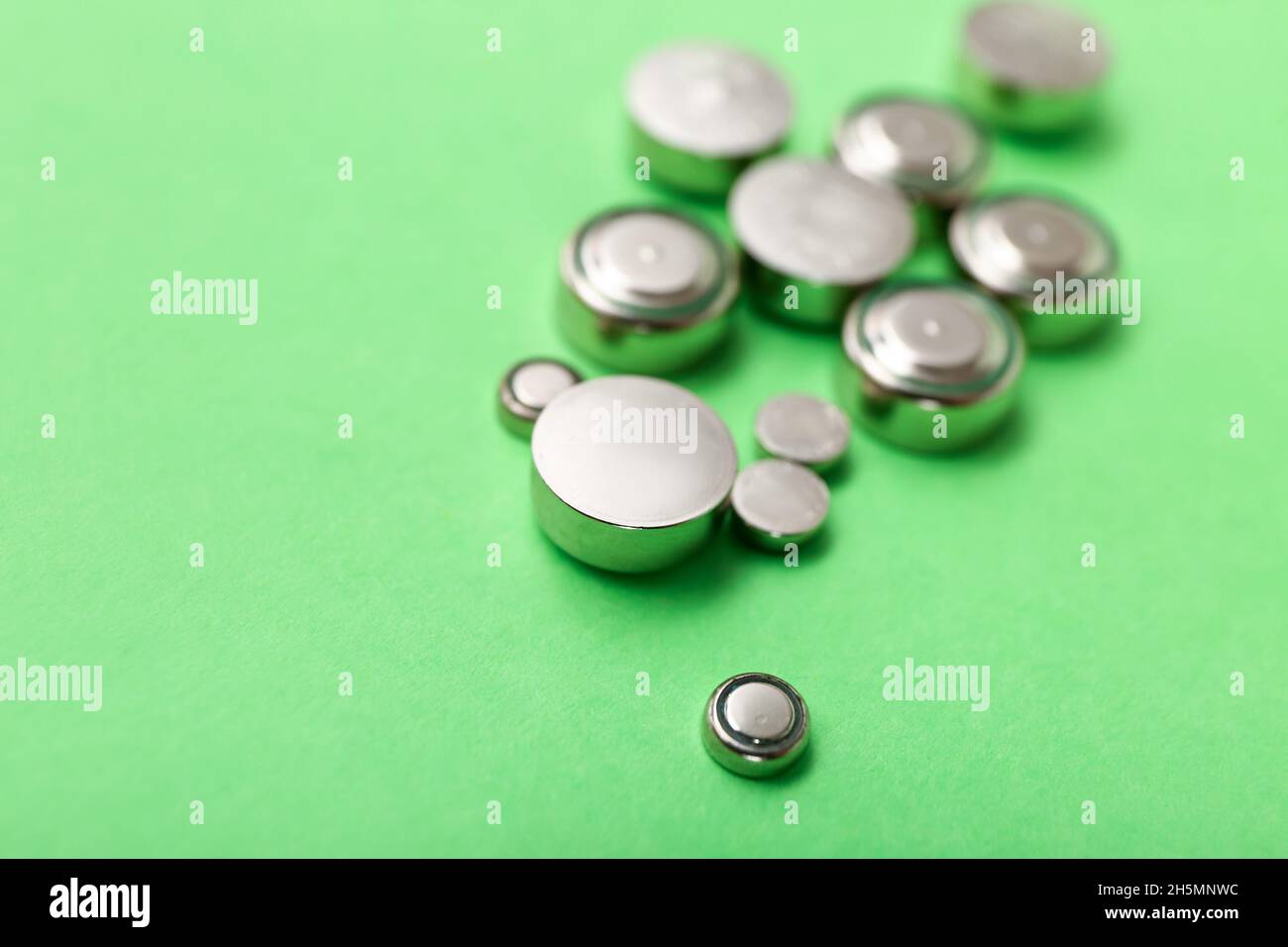 Lithium button cell batteries on green background, closeup Stock Photo
