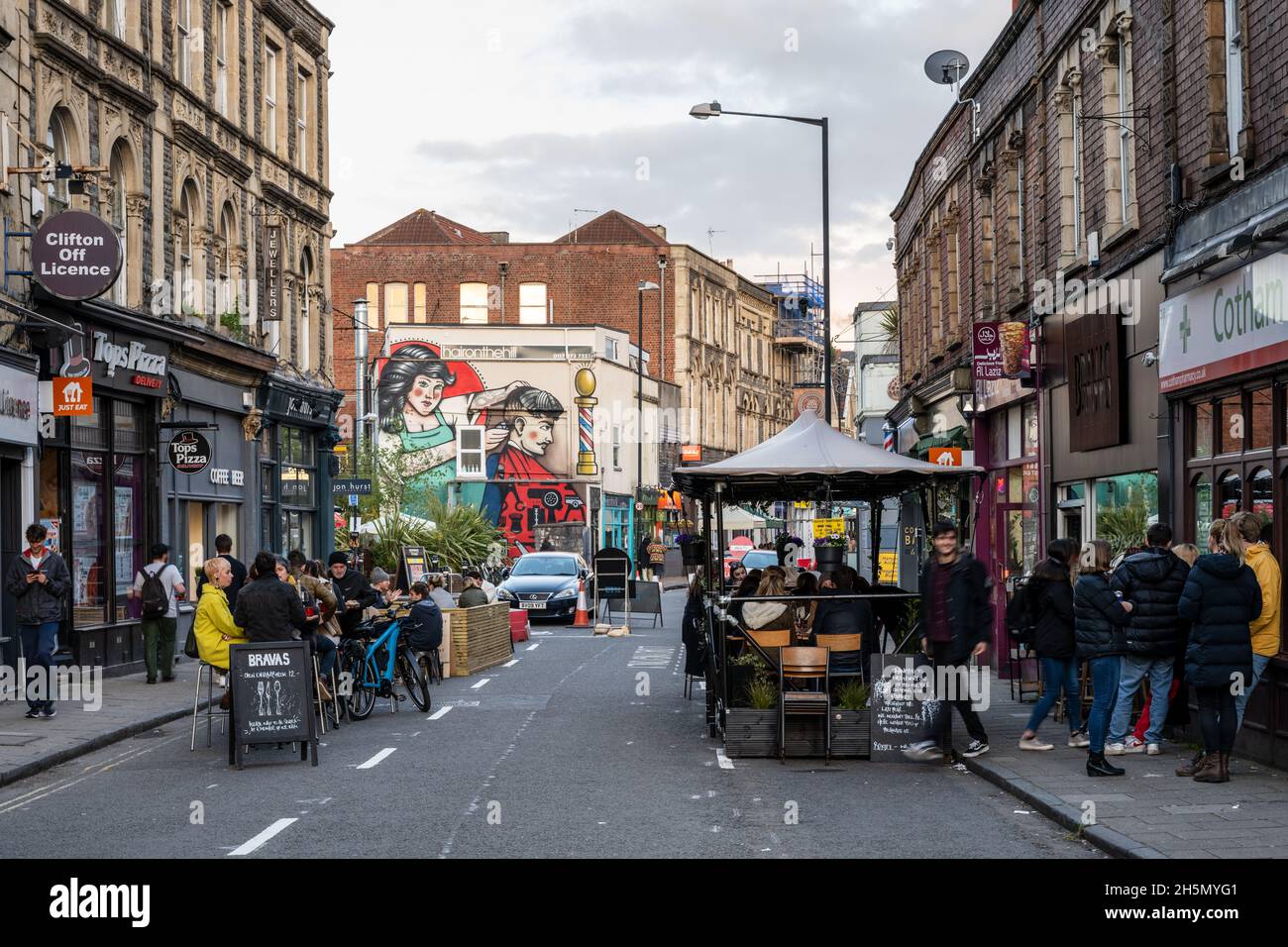 People sit at outdoors dining tables outside restaurants during a trial pedestrianisation of Cotham Hill in Bristol. Stock Photo