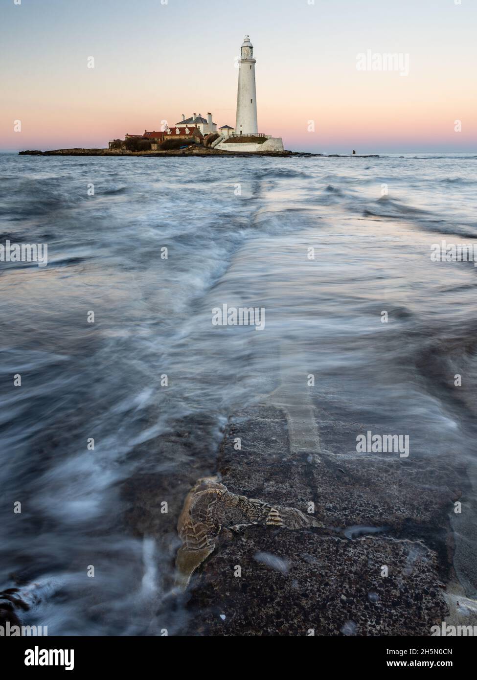 Waves flow accross the St Mary's Island Causeway at dusk, with St Mary's Lighthouse behind, on the Whitley Bay coast of Tyneside. Stock Photo
