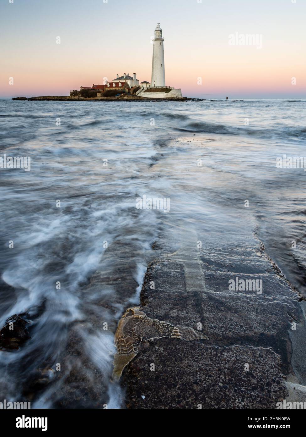 Waves flow accross the St Mary's Island Causeway at dusk, with St Mary's Lighthouse behind, on the Whitley Bay coast of Tyneside. Stock Photo