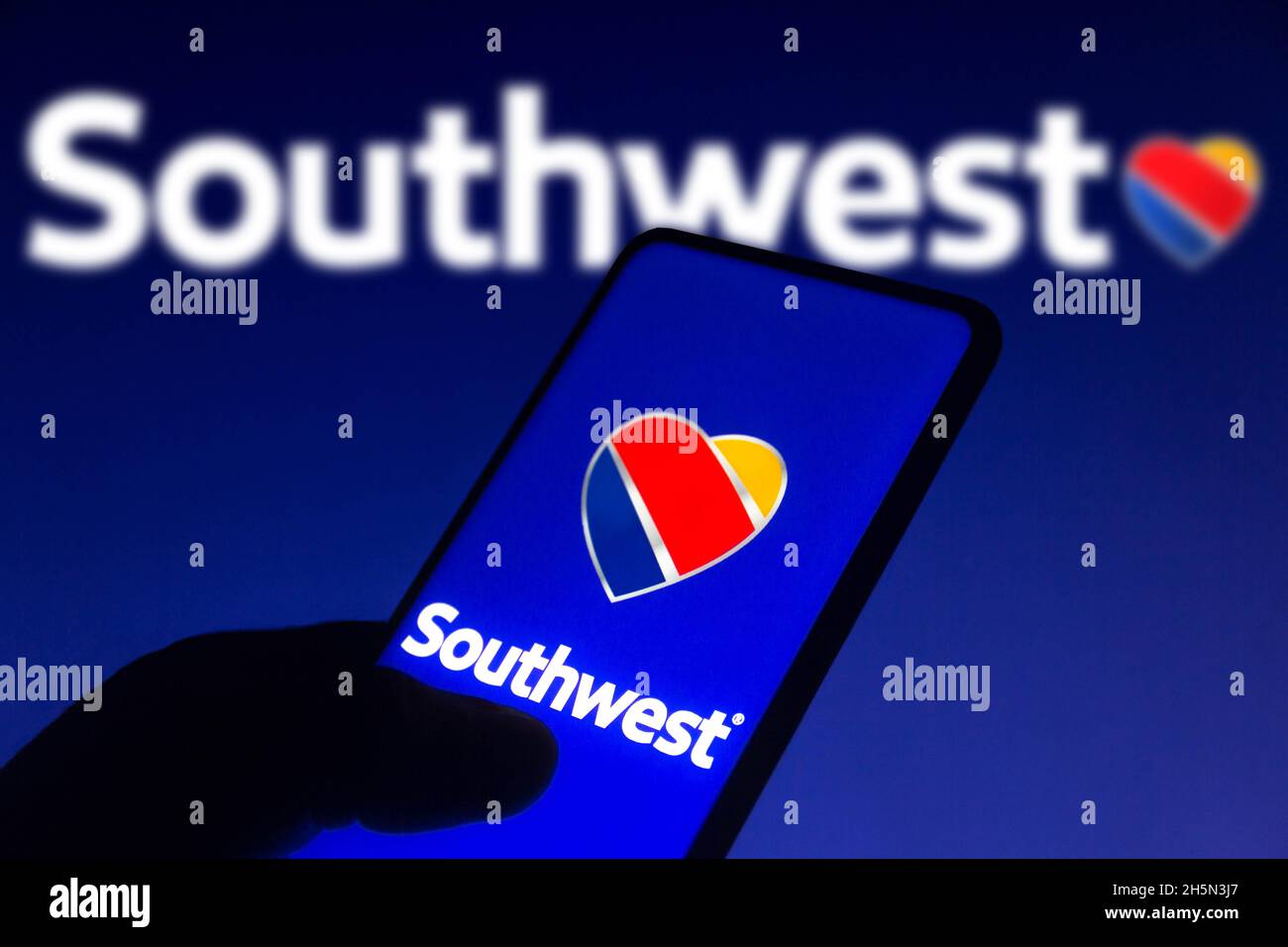 In this photo illustration the Southwest Airlines logo seen displayed on a smartphone screen and in the background. Stock Photo