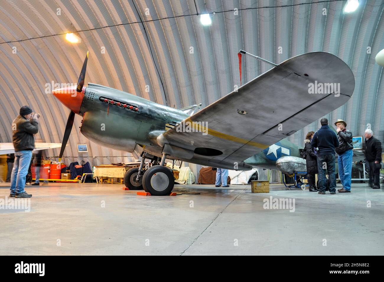 Hangar 11 Curtiss P-40 Warhawk inside the hangar at North Weald, Essex, UK. Wearing a temporary paint scheme for the film Red Tails. Weathered effect Stock Photo