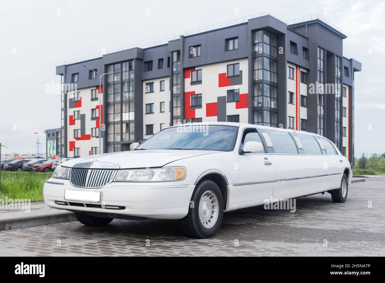 White limousine luxury long car for celebrations and celebrations against the backdrop of a modern city building. Stock Photo