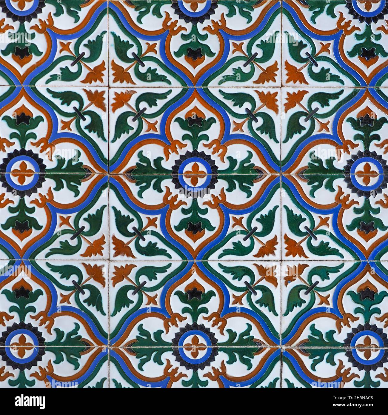 Fragment of building wall with glazed ceramic tiles, embossed vintage Mudejar, close up. Traditional ornate Spanish architecture. Abstract background. Stock Photo