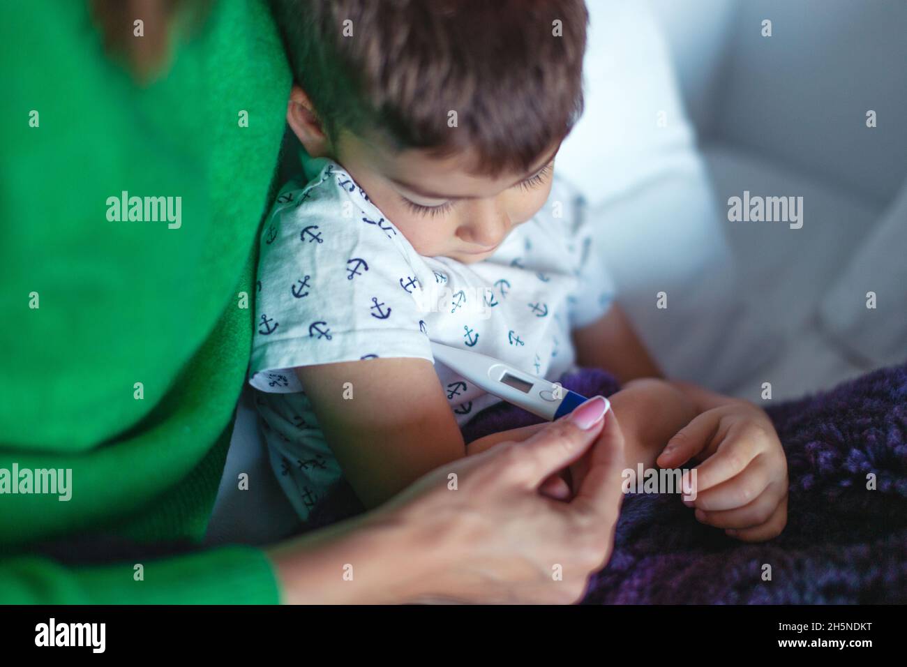 Mother taking temperature to son at home closeup Stock Photo