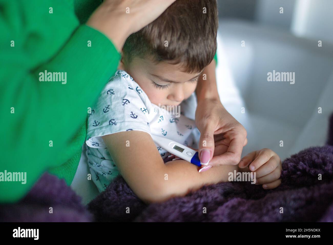 Mother taking temperature to little son at home closeup Stock Photo
