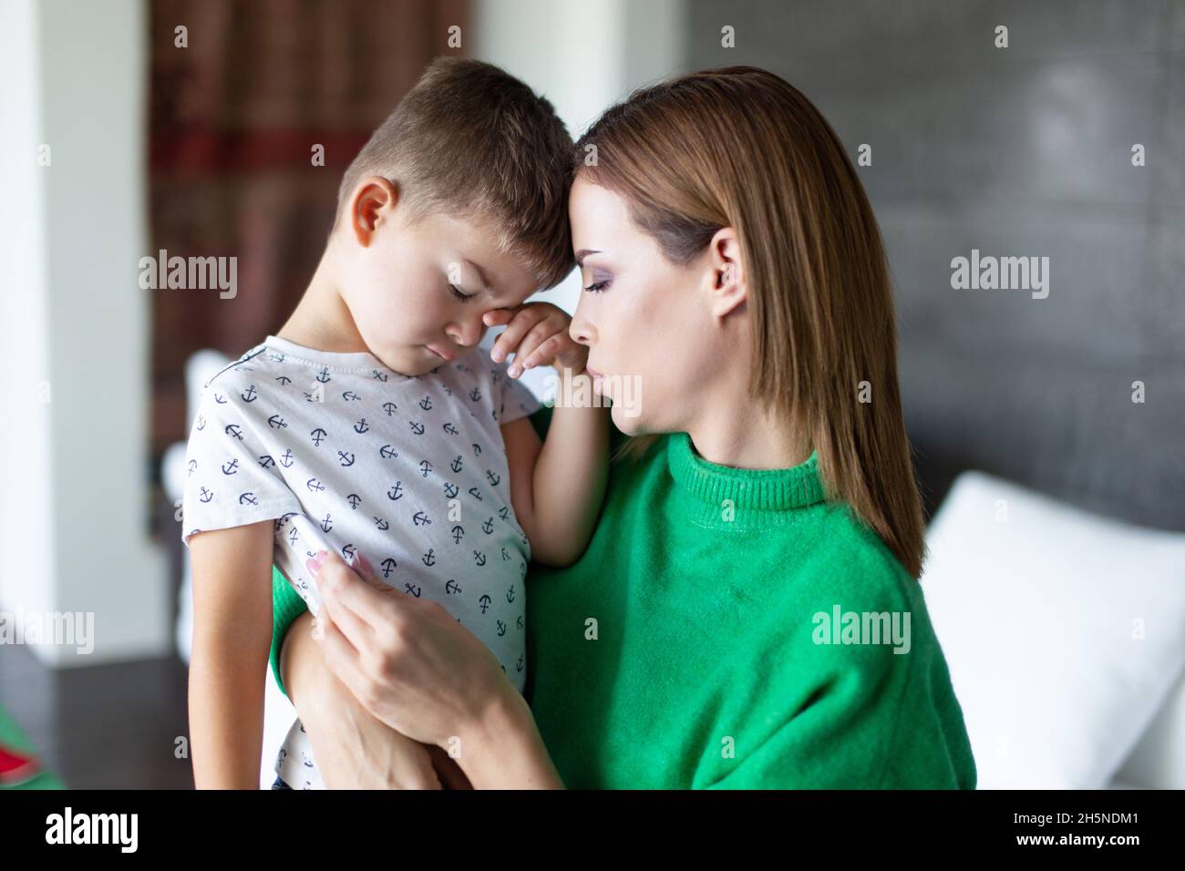 Sad mother taking temperature to son at home closeup Stock Photo