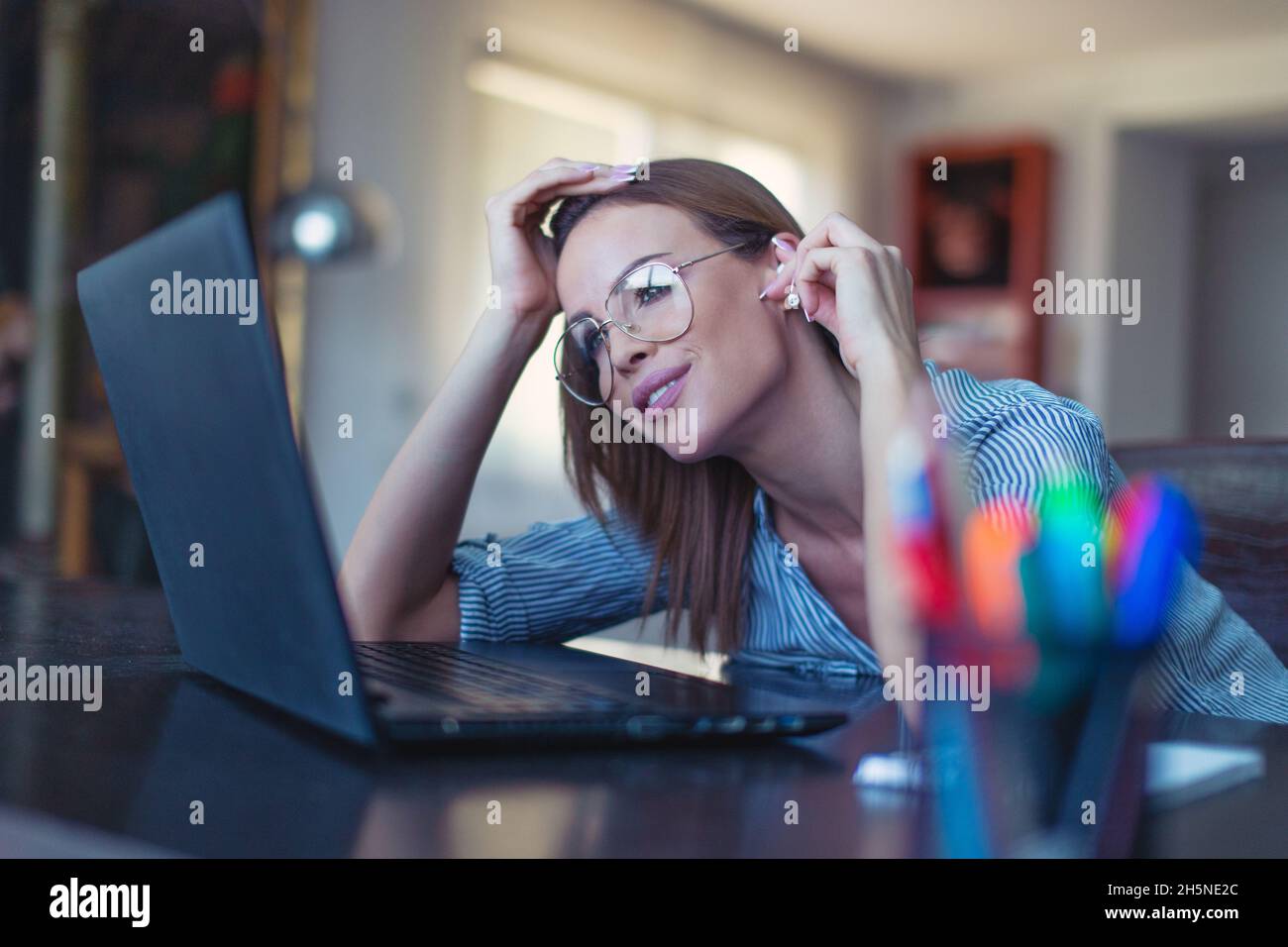 Young Caucasian woman with hands free device listening music at laptop Stock Photo
