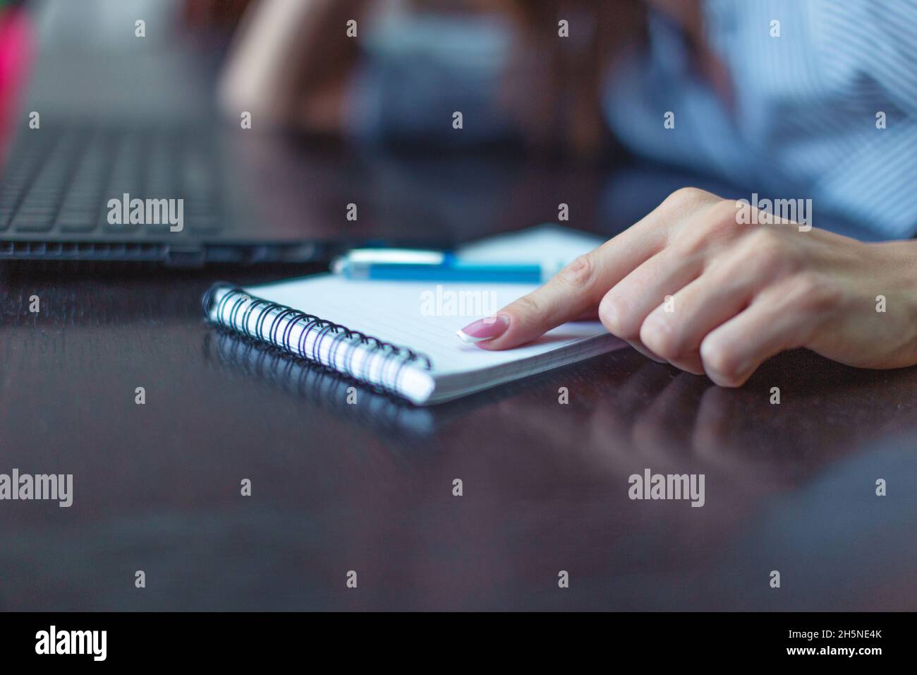 Woman hand pointing to blank notebook on desk closeup Stock Photo