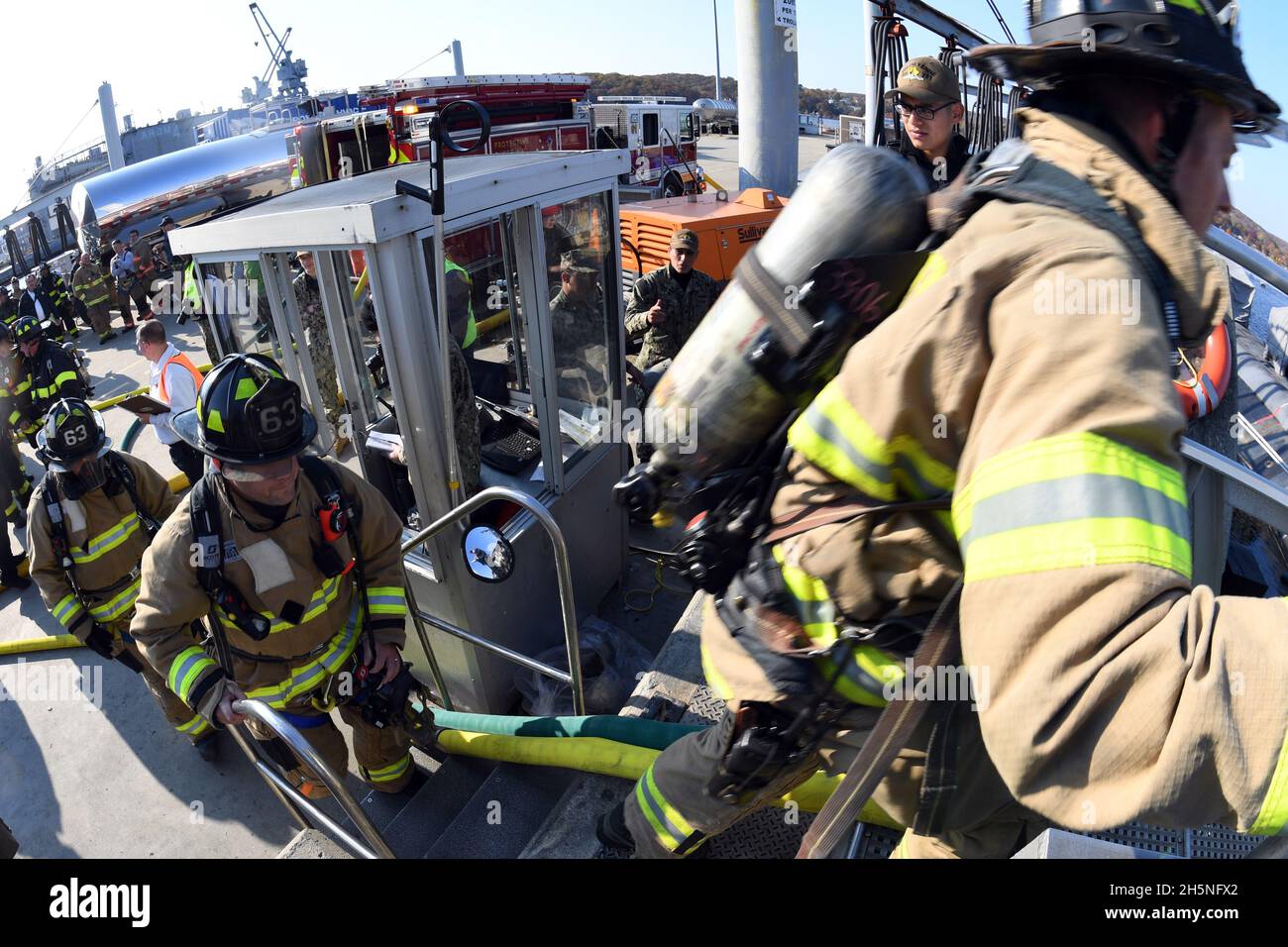 211110-N-GR655-449 GROTON, Conn. (November 10, 2021) – U.S. Navy firefighters cross the bow of the USS Cheyenne (SSN 773) during a large-scale fire response exercise on board Naval Submarine Base New London in Groton, Conn., Nov. 10, 2021. The exercise, hosted by Naval Submarine Support Facility (NSSF) New London, Cheyenne, and base leadership, offered more than a dozen regional firefighter and first responder organizations the opportunity to experience shipboard firefighting and Navy best practices. (U.S. Navy photo by Chief Petty Officer Joshua Karsten/RELEASED) Stock Photo